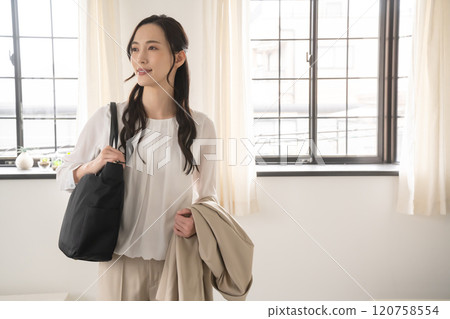 Woman with shoulder bag and jacket indoors 120758554