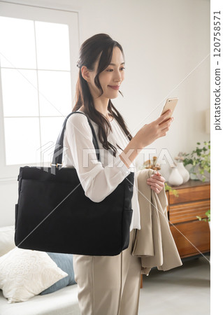 一位女士在準備外出室內時看著智慧型手機 一位女士在準備外出室內時看著智慧型手機 120758571