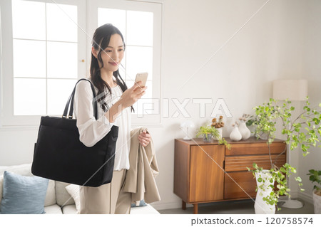 一位女士在準備外出室內時看著智慧型手機 120758574
