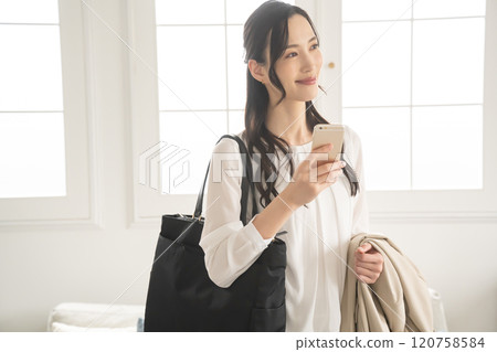 一位女士在準備外出室內時看著智慧型手機 一位女士在準備外出室內時看著智慧型手機 120758584