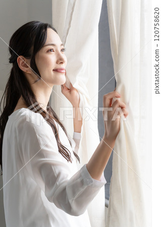 Woman opening curtain Woman opening curtain 120758620