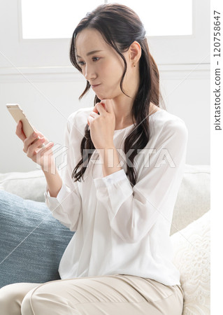 A woman watching a smartphone A woman watching a smartphone 120758647