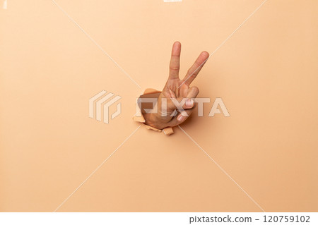 man hand showing two fingers,victory sign gesture on a brown background, 120759102