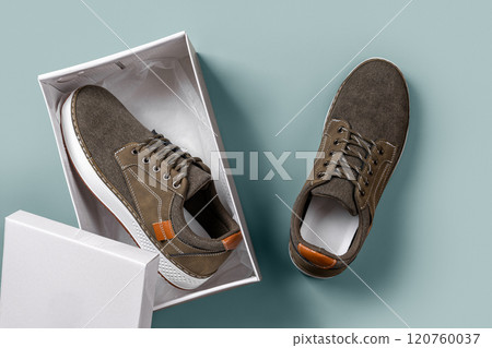 Khaki canvas shoes in a box over silver blue background. Khaki canvas shoes in a box over silver blue background. 120760037