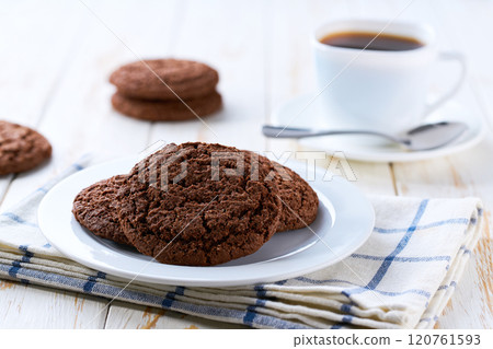 American chocolate cookies and coffee on a light kitchen table, selective focus. American chocolate cookies and coffee on a light kitchen table, selective focus. 120761593