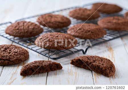 Freshly baked chocolate brownie cookies with cracks cooling on a black wire rack, with in a light kitchen table, selective focus. Freshly baked chocolate brownie cookies with cracks cooling on a black wire rack, with in a light kitchen table, selective focus. 120761602