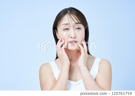 Middle-aged woman with a tired expression doing skin care 120761759