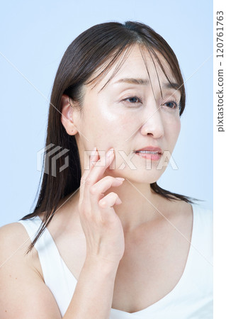 一位中年婦女一臉疲憊地做皮膚護理 120761763