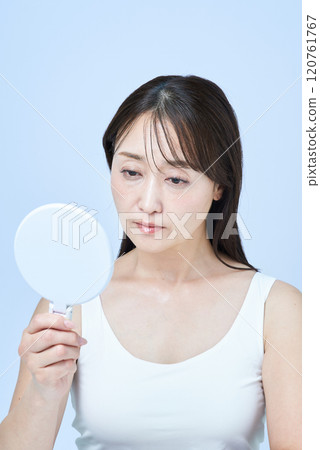 一位中年婦女一臉疲憊地做皮膚護理 一位中年婦女一臉疲憊地做皮膚護理 120761767