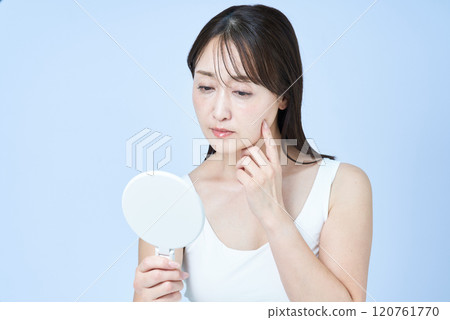 Middle-aged woman with a tired expression doing skin care Middle-aged woman with a tired expression doing skin care 120761770