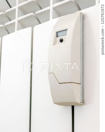 Smart heat meter on white radiator 120761972