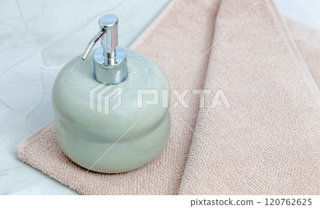 Ceramic soap dispenser and folded towel on white marble background. Ceramic soap dispenser and folded towel on white marble background. 120762625