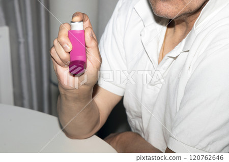 Man holding asthma inhaler in his hands. 120762646