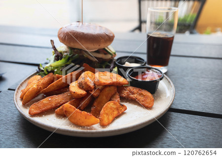 Plate with burger and french fries, ketchup and mayonnaise and cola on the table. Plate with burger and french fries, ketchup and mayonnaise and cola on the table. 120762654