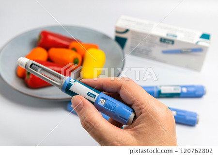 Hands holding Ozempic Insulin injection pen for diabetics and weight loss 120762802