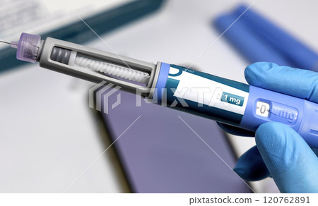 Hands in surgical gloves holding Ozempic Insulin injection pen for diabetics. 120762891