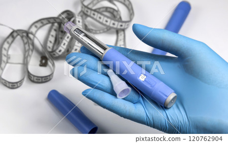 Hands in surgical gloves holding Ozempic Insulin injection pen for diabetics. 120762904