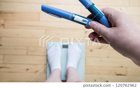 Ozempic Insulin injection pen for diabetics and weight loss. Woman weighs herself and holds Ozempic in her hand. Ozempic Insulin injection pen for diabetics and weight loss. Woman weighs herself and holds Ozempic in her hand. 120762962