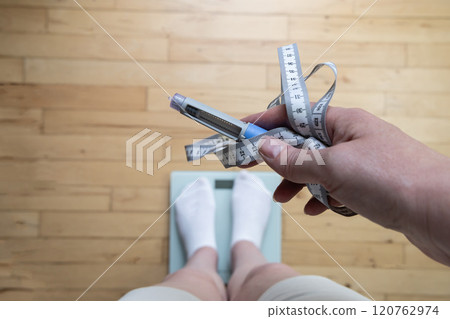Ozempic Insulin injection pen for diabetics and weight loss. Woman weighs herself and holds Ozempic in her hand. 120762974