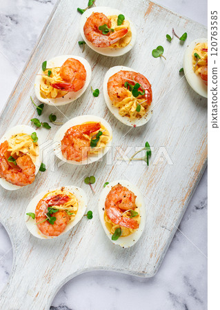 Boiled eggs stuffed with yolk and seasoned with mayonnaise, stuffed eggs with shrimp, on a white wooden chopping board, selective focus, close-up, without people, 120763585