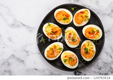 Boiled eggs stuffed with yolk and seasoned with mayonnaise, stuffed eggs with shrimp, on a black plate, selective focus, close-up, no people, 120763618