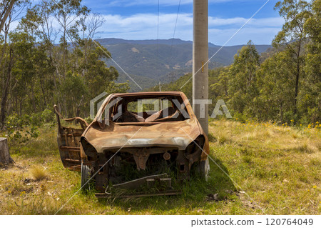 An abandoned and burnt out car in a remote area 120764049