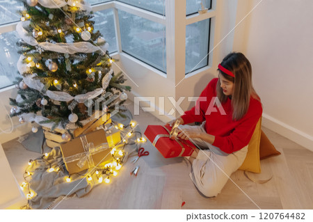 Red sweater woman packing red box for decorating her Christmas tree in the apartment. 120764482