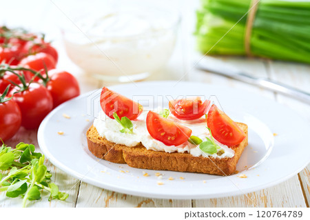 Healthy breakfast, bruschetta with ricotta cheese, and cherry tomatoes on a kitchen table. 120764789