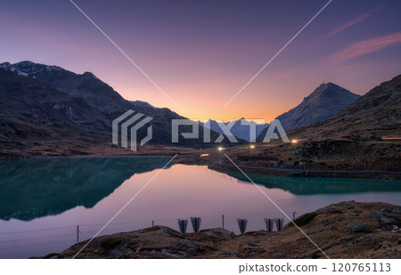 Mountain peaks mirrored in a tranquil alpine lake at twilight 120765113