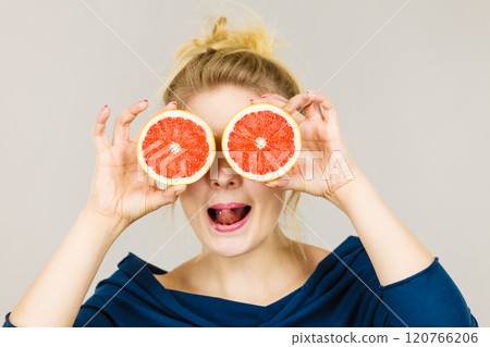 Woman holding fruit grapefruit half on eyes Woman holding fruit grapefruit half on eyes 120766206
