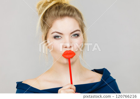 Funny woman holding big red lips on stick Funny woman holding big red lips on stick 120766216