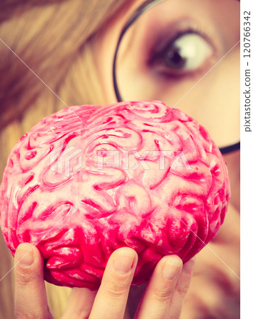 Woman holding magnifying glass investigating brain 120766342