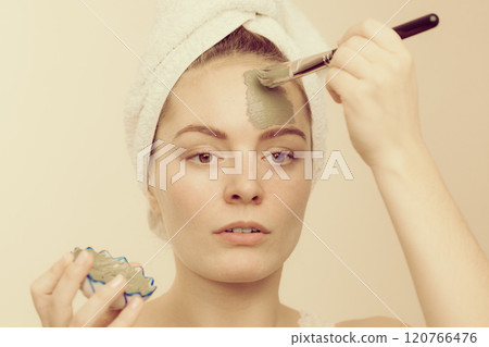 Woman applying with brush clay mud mask to her face Woman applying with brush clay mud mask to her face 120766476