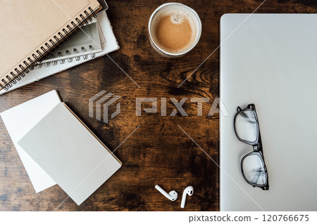 Minimal workspace with coffee cup, spiral notebooks, blank paper, glasses, wireless earbuds, and wooden desk Minimal workspace with coffee cup, spiral notebooks, blank paper, glasses, wireless earbuds, and wooden desk 120766675