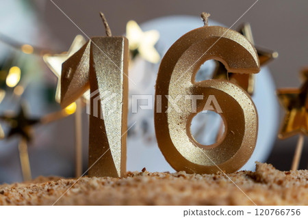 Golden sixteen birthday candles burning on cake with star decorations Golden sixteen birthday candles burning on cake with star decorations 120766756