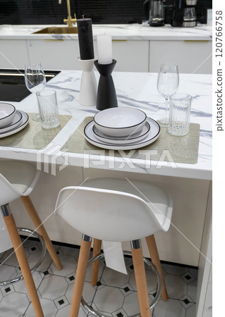 Modern kitchen counter with tableware and candles preparing for dinner Modern kitchen counter with tableware and candles preparing for dinner 120766758