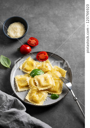 Homemade ravioli pasta with cheese, tomatoes and basil in a plate on a dark background with napkin 120766920