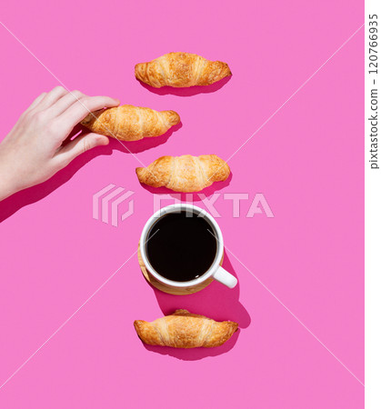 Hand holding fresh mini croissant or bagel on pink background with shadow and cup of espresso coffee Hand holding fresh mini croissant or bagel on pink background with shadow and cup of espresso coffee 120766935
