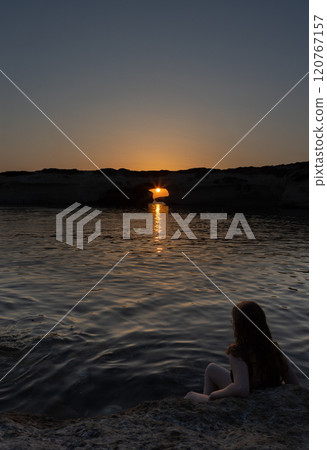 Woman Admiring Sunset through Rock Arch 120767157