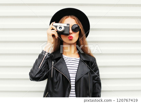 Stylish young woman with camera wearing elegant black hat, leather jacket on white background Stylish young woman with camera wearing elegant black hat, leather jacket on white background 120767419
