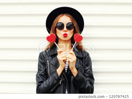 Fashion portrait young woman with red lips sending kiss with lollipop heart in black hat on white Fashion portrait young woman with red lips sending kiss with lollipop heart in black hat on white 120767425