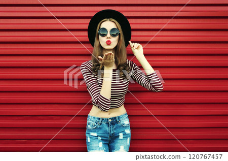 stylish young woman blowing her red lips sending air kiss wearing a black round hat on a background stylish young woman blowing her red lips sending air kiss wearing a black round hat on a background 120767457