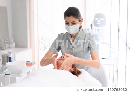 Female cosmetologist massaging relaxed woman's Female cosmetologist massaging relaxed woman's 120768080