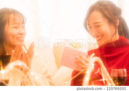Two women giving gifts at a home party 120769203
