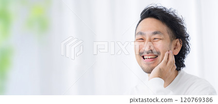 一名中年男子看著鏡頭,一邊照鏡子一邊照顧自己的皮膚的橫幅 一名中年男子看著鏡頭,一邊照鏡子一邊照顧自己的皮膚的橫幅 120769386