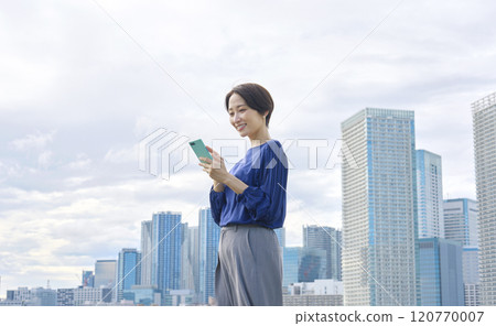 Woman operating a smartphone outdoors Woman operating a smartphone outdoors 120770007
