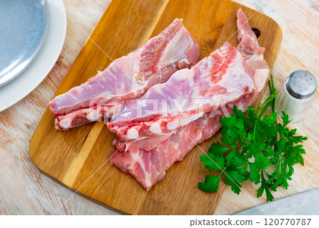Fresh raw pork ribs on kitchen board with parsley, meat with bone. Cooking delicious food or grilling Fresh raw pork ribs on kitchen board with parsley, meat with bone. Cooking delicious food or grilling 120770787