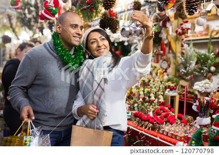 Emotional happy couple buying christmas balls at christmas fair Emotional happy couple buying christmas balls at christmas fair 120770798