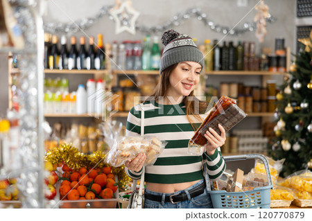 While shopping on eve of New Year holidays, young lady buys sweets for festive party While shopping on eve of New Year holidays, young lady buys sweets for festive party 120770879