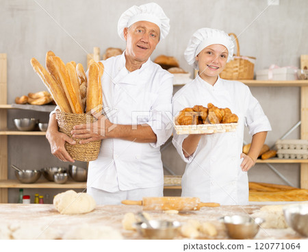 Smiling artisan bakers showcasing baguettes and croissants 120771064